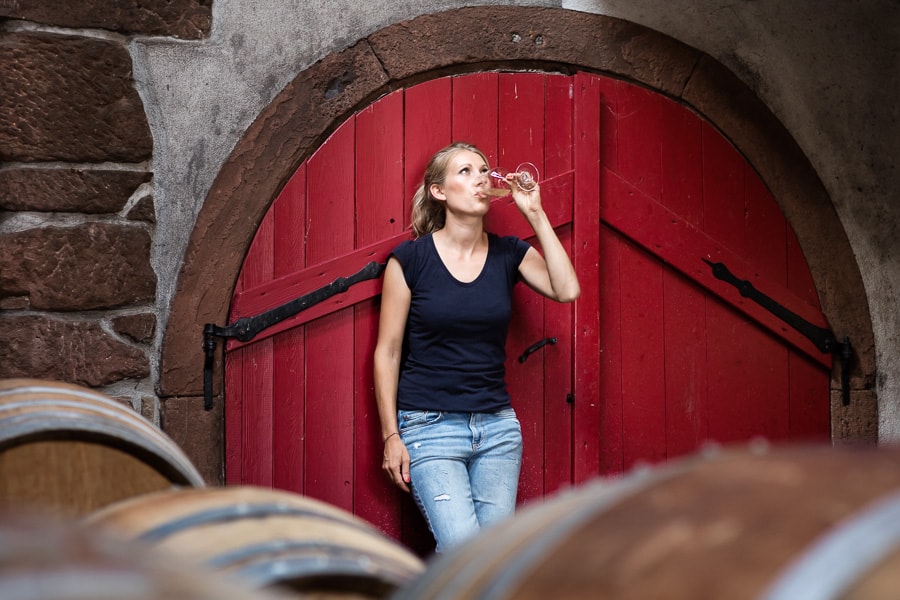 Eine junge Frau trinkt Wein vor einem roten Tor